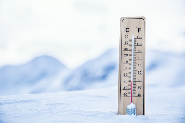 Thermometer auf den Bergen im Schnee zeigt Temperaturen unter Null an. Niedrige Temperaturen in Grad Celsius und Fahrenheit.