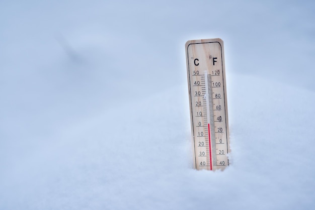 Thermometer auf Schnee mit niedrigen Temperaturen in Celsius oder Fahrenheit im Winter.