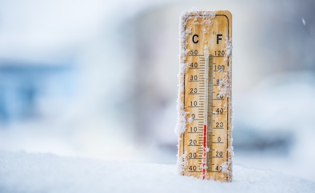 Thermometer auf Schnee zeigt niedrige Temperaturen in Celsius oder Fahrenheit an.