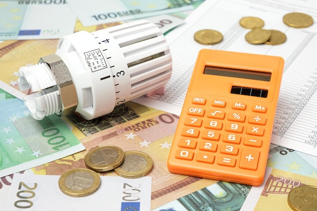 Thermostatischer Ventilkopf-Rechner auf Euro-Banknoten-Hintergrund Steigende Verbrauchskosten für Strom Energiekonzept Preiserhöhung Heizungskrise Versorgungsrechnung Einsparung Erhaltung Inflation