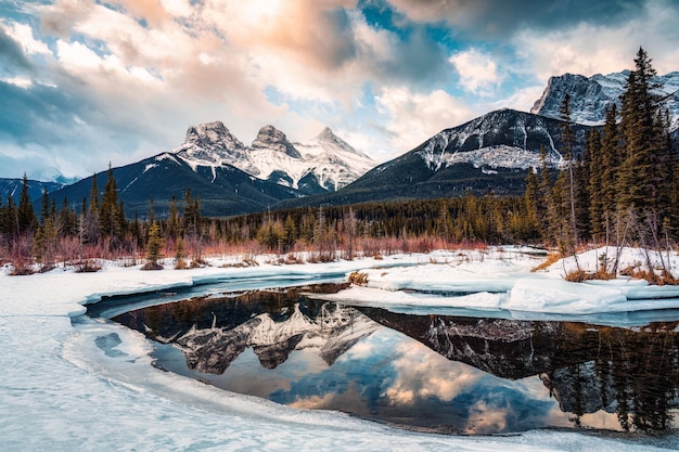 Three Sisters Mountains mit schneebedeckter Bow River Reflexion am Morgen im Winter bei Canmore