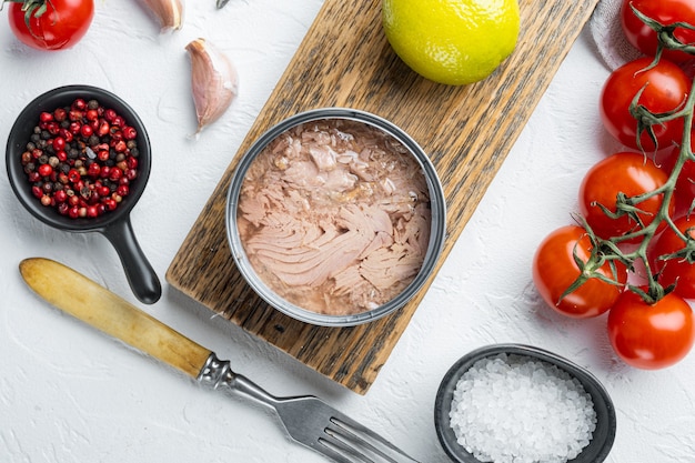 Thunfisch in einer Dose, ganz und gehackt, auf Holzschneidebrett, auf Weiß