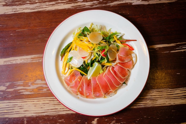 Thunfisch-Tataki mit sommerlichem Mangosalat Panasiatische orientalische Küche auf Holztisch