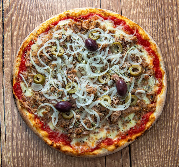 Thunfischpizza mit Auberginen, Zwiebelringen und schwarzen Oliven, serviert über rustikalem Holztisch.
