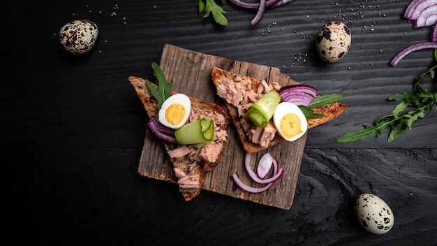 Thunfischsalat Sandwiches auf Schneidebrett Bruschetta Toast mit Vollkornbrot Dosenthunfisch Wachteleier und Zwiebeln Gurke