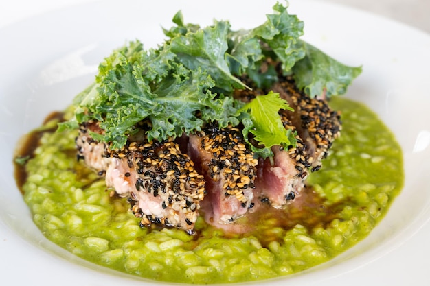 Thunfischsteak mit Sesam und Caprese-Risotto auf Pesto-Sauce-Teller. Speisekarte des Gourmetrestaurants