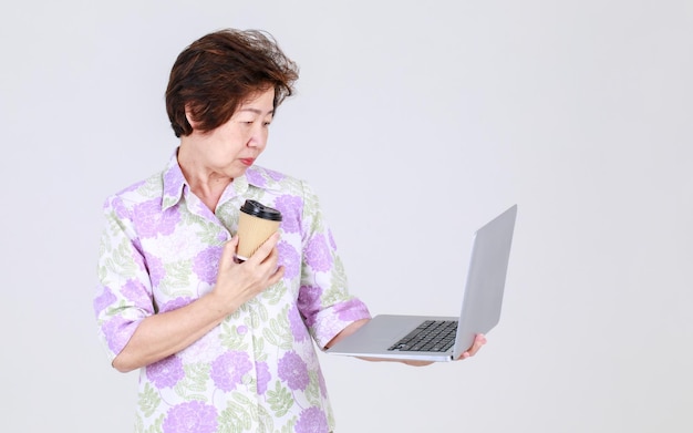 Tia asiática sênior como professora idosa jogando laptop de negócios para explicar promoção de venda e mensagem publicitária de dispositivo eletrônico. Avó apresenta informações de tecnologia para adulto aposentado.