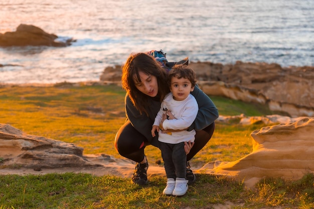 Tia da criança brincando com ele na costa à beira-mar ao pôr do sol