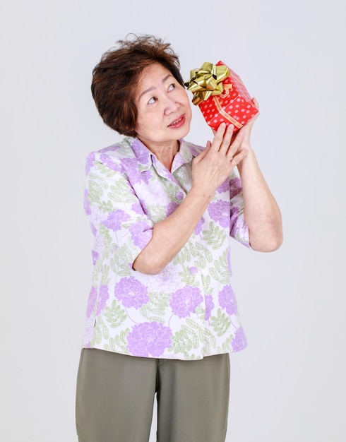 Tia idosa, mulher asiática sênior segurando caixa de presente no conceito de fundo branco