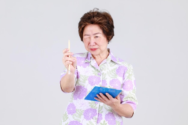 Tia idosa, professora idosa asiática sênior gravando ideia criativa escrevendo um memorando no quadro de notas no conceito de fundo branco