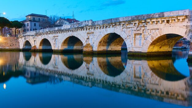 Foto tiberiusbrücke in rimini in der abenddämmerung und ihre reflexion im warer-spiegel, italien