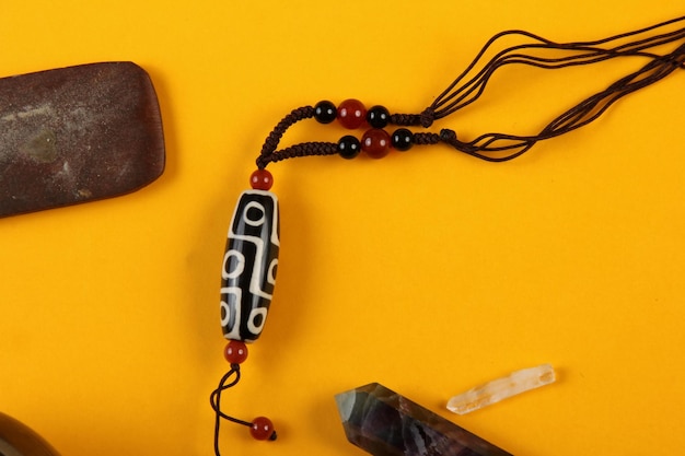 Tibetische Dzi-Perlen-Amulett-Halskette, tibetische Klangschale auf gelbem Hintergrund