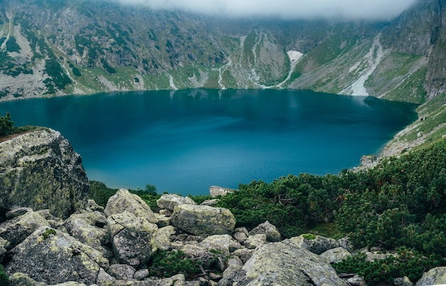 Tiefblauer oberflächensee in bergnebellandschaft. tatra-gebirge, czarny staw, polen