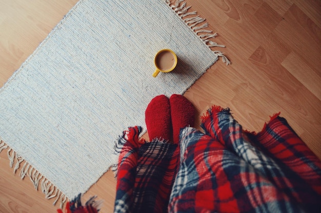 Tiefes Teil einer Frau mit Kaffeetasse auf dem Holzboden zu Hause