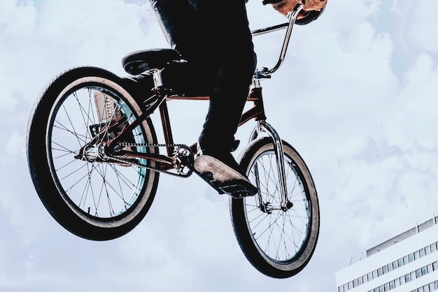 Tiefes Teil eines Mannes, der gegen den Himmel Fahrrad fährt