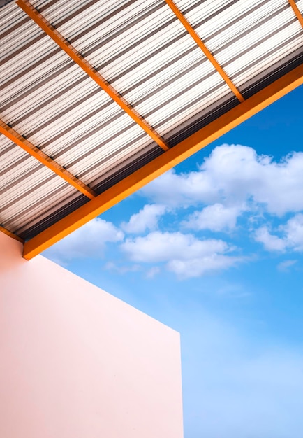 Tiefwinkelansicht des Arkadendaches mit beigem Lagergebäude gegen Wolken am blauen Himmel