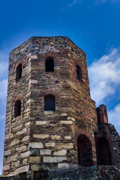 Tiefwinkelansicht des aus Stein gebauten byzantinischen Turms mit Fensteröffnungen gegen den blauen Himmel