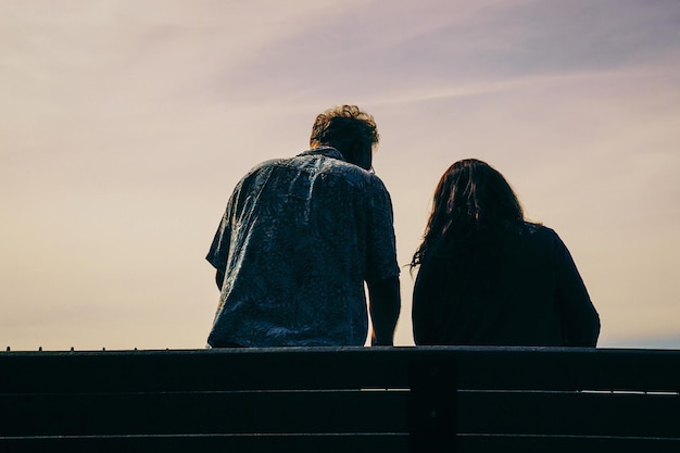 Foto tiefwinkelansicht von einem mann und einer frau, die an einem sonnigen tag gegen den himmel sitzen