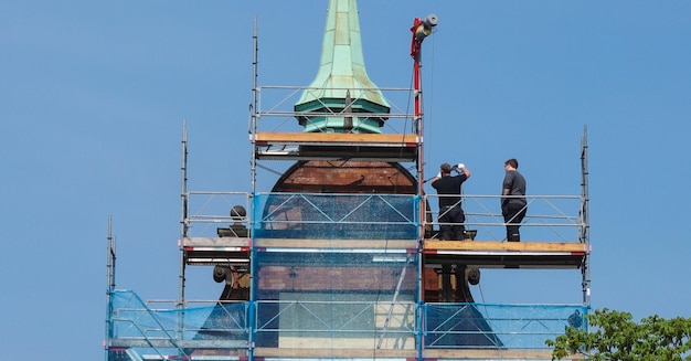 Tiefwinkelansicht von Männern, die gegen einen klaren blauen Himmel arbeiten