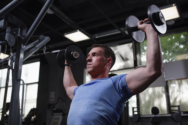 Foto tiefwinkelaufnahme eines bodybuilders, der im fitnessstudio mit hanteln trainiert