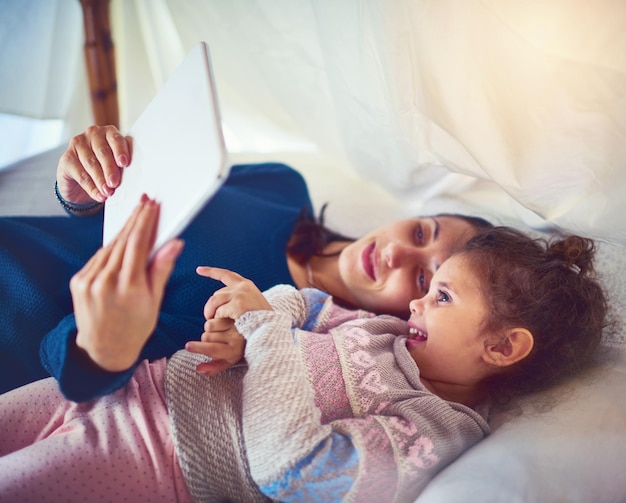 Tiempo de aprendizaje interactivo Fotografía de una madre y su pequeña hija usando una tableta digital juntas en casa