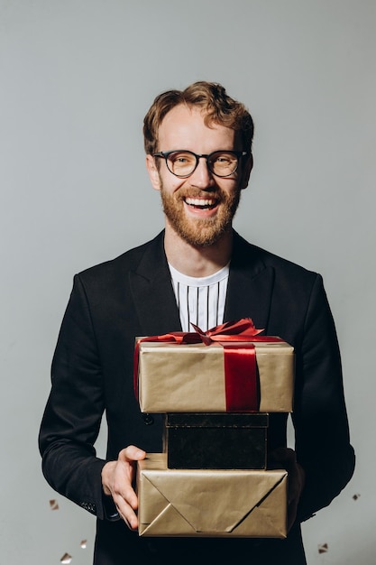 Tiempo de celebración Retrato de un tipo feliz sosteniendo una pila de cajas presentes aisladas sobre fondo blanco en el estudio