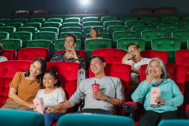 Foto un tiempo de cine familiar alegre padres y hijos asiáticos viendo una película con palomitas de maíz