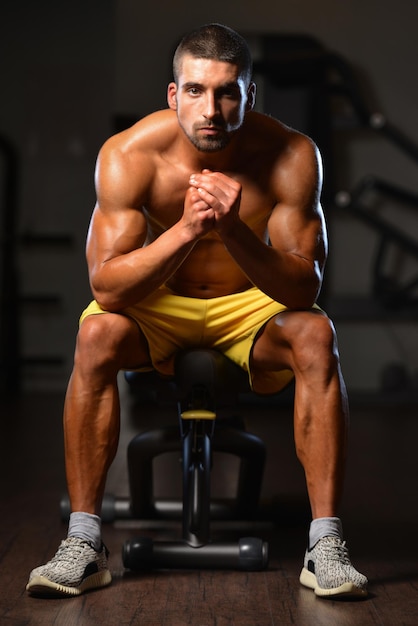 Tiempo de descanso confiado joven musculoso descansando en el gimnasio del club saludable después de hacer ejercicio