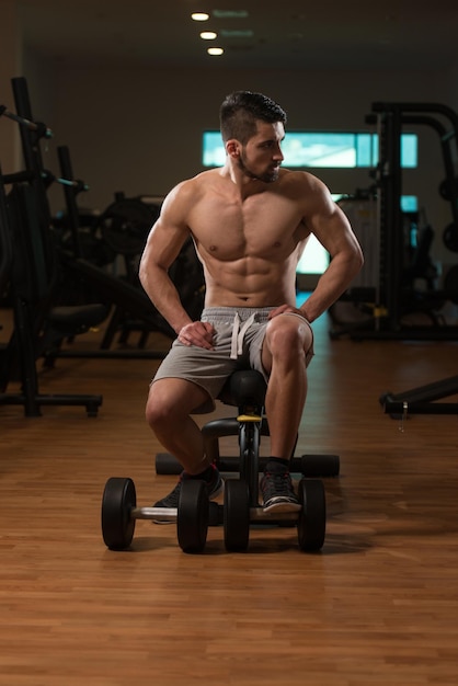 Tiempo de descanso confiado joven musculoso descansando en el gimnasio del club saludable después de hacer ejercicio