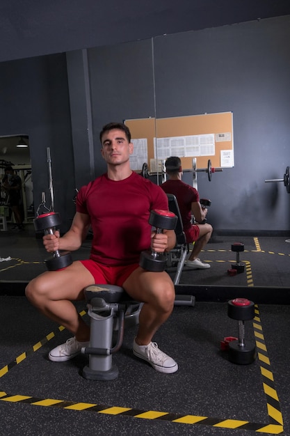 Tiempo de descanso joven en ropa deportiva sentado en el gimnasio