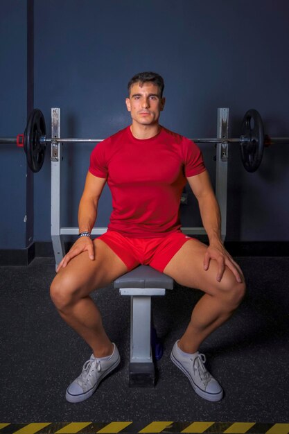 Tiempo de descanso joven en ropa deportiva sentado en el gimnasio