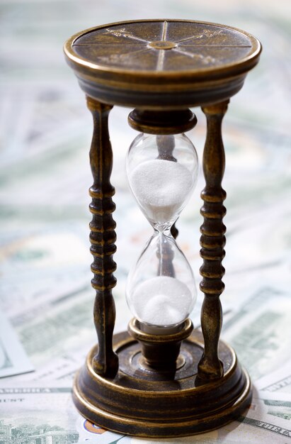 Foto el tiempo es dinero. reloj de arena y dólares estadounidenses. concepto de dinero