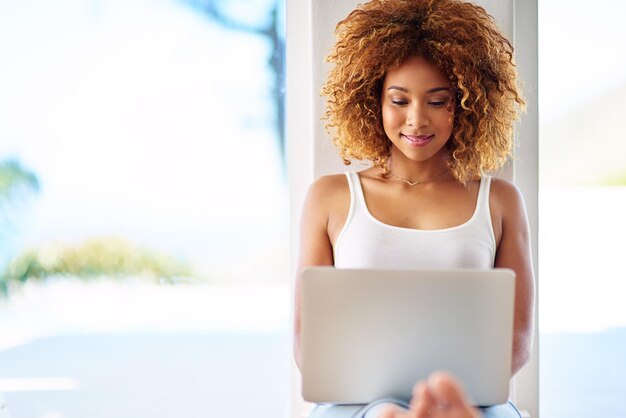 Tiempo de fin de semana y la vida es fácil Foto de una mujer joven usando una computadora portátil en el piso de su casa