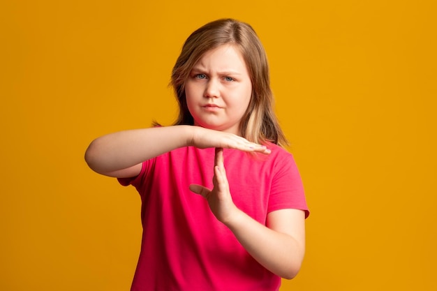 Tiempo de huelga de niños pausa pausa señal de mano preocupada niña en rosa mostrando el signo t mirando