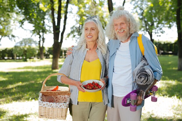 Foto tiempo juntos. anciano positivo abrazando a la esposa mientras hace un picnic con ella