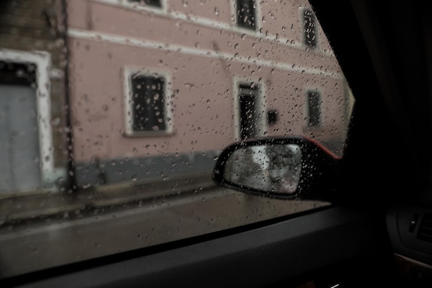 Tiempo lluvioso en vista de la ciudad a través de la ventana del coche cubierta con gotas