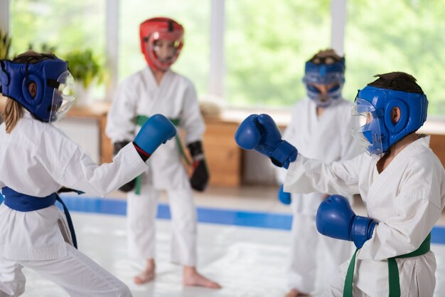 Tiempo de lucha. Atlético fuerte niño y niña en cascos protectores y guantes de boxeo peleando