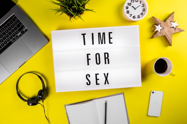 Tiempo para el mensaje de caja de luz sexual en el moderno escritorio de oficina amarillo con reloj despertador