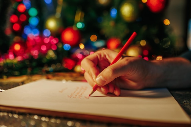 Foto tiempo de navidad fondo borroso envoltura de regalo y oropel mano de escritura humana irreconocible