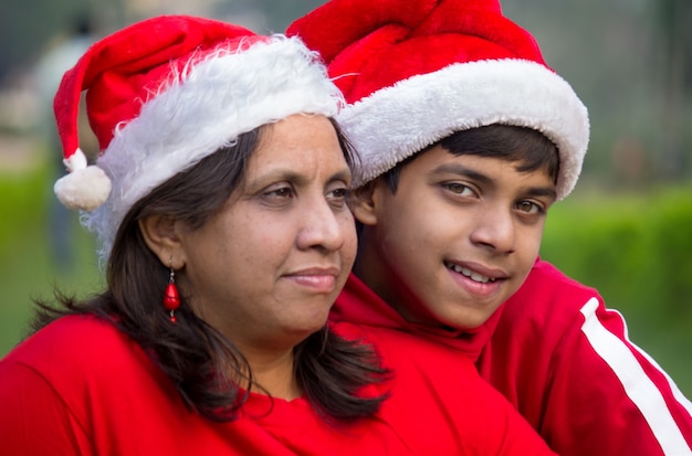 Tiempo de Navidad Retrato de una madre y su hijo con gorros de Papá Noel y camisetas rojas durante la temporada festiva