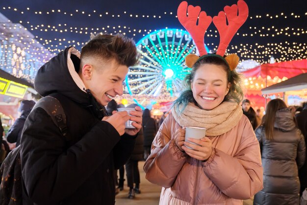 Tiempo de Navidad, vacaciones de año nuevo. Los jóvenes, una pareja de adolescentes divirtiéndose en el mercado de Navidad