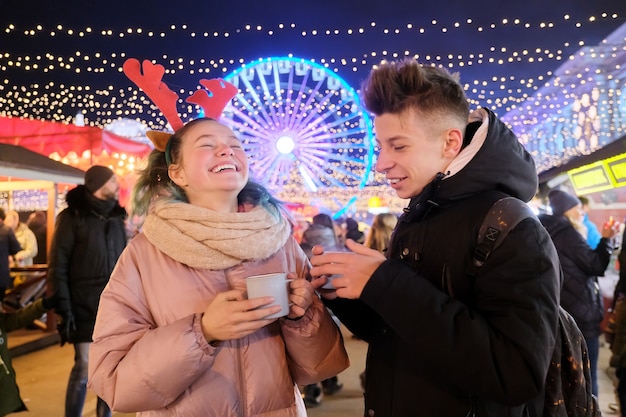 Tiempo de Navidad, vacaciones de año nuevo. Los jóvenes, una pareja de adolescentes divirtiéndose en el mercado de Navidad