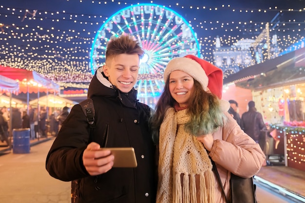 Tiempo de Navidad, vacaciones de año nuevo. Los jóvenes, una pareja de adolescentes divirtiéndose en el mercado de Navidad