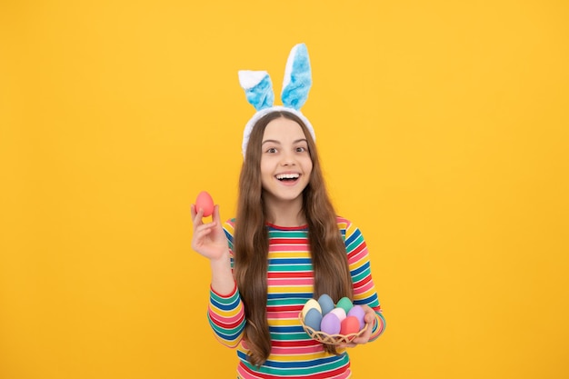 Tiempo de Pascua para divertirse adorable niño divertido en la búsqueda de huevos vacaciones de primavera de pascua feliz niña adolescente usar orejas de conejo feliz pascua infancia felicidad niño en orejas de conejo sostener huevos pintados