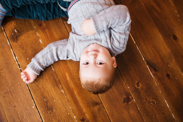 Tiempo sin preocupaciones. Vista superior de un niño acostado en el piso de madera y sonriendo