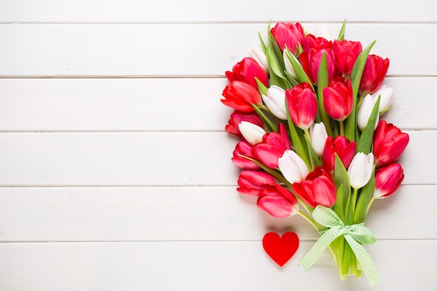 Tiempo de primavera. Ramo de tulipanes rojos sobre fondo blanco de madera.