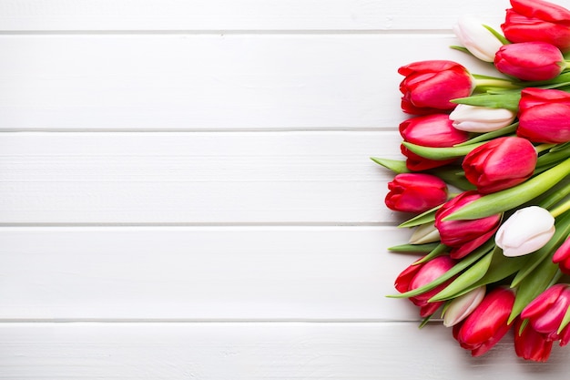 Tiempo de primavera. Ramo de tulipanes rojos sobre fondo blanco de madera.