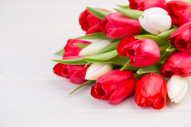 Tiempo de primavera. Ramo de tulipanes rojos sobre la superficie de madera blanca.
