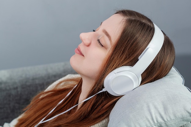 Tiempo de relajación en el sofá hermosa joven tumbada en el sofá y escuchando la música con