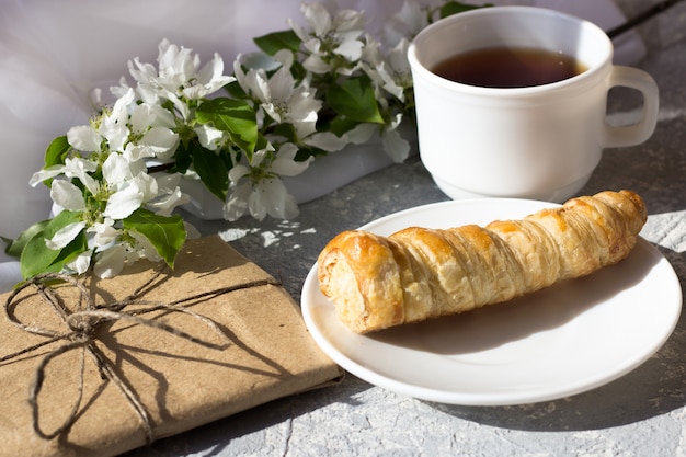 Tiempo relajante y felicidad con una taza de té con flores frescas de primavera. Té de la mañana con un pastel en un día cálido y soleado.